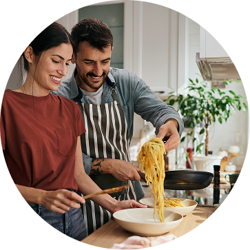 A couple cooking pasta together in their kitchen